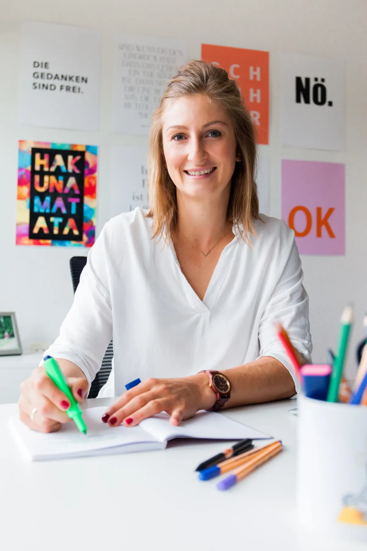 Dr. Katharina Ptack arbeitet am Schreibtisch mit Notizbuch und Marker