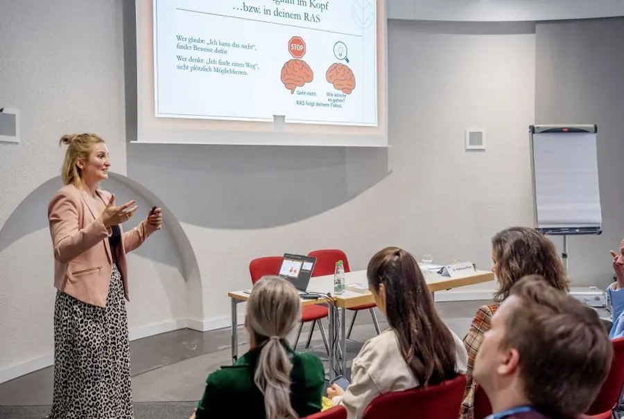 Dr. Katharina Ptack hält einen Vortrag vor einer Gruppe von Teilnehmenden in einem Seminarraum